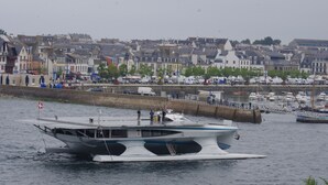 Ein Boot liegt an einem Ufer mit Gebäuden im Hintergrund.