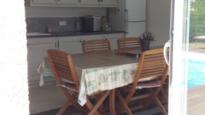Een eethoek met een tafel, stoelen, een koelkast en kastjes.
