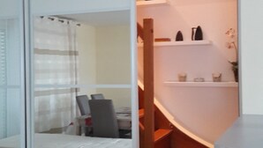 Een modern interieur met een witte schuifdeur, een houten trap en een klein plankje met decoratieve objecten.