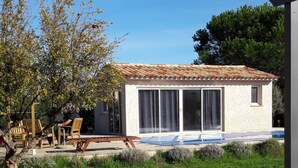 Een modern huis met een pannendak, een terras met een houten bank en een gazon.