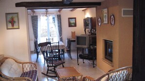 A living room with wicker furniture, a dining table, and a fireplace.