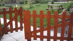 A wooden fence, a picnic table, and a stone wall in a garden setting.