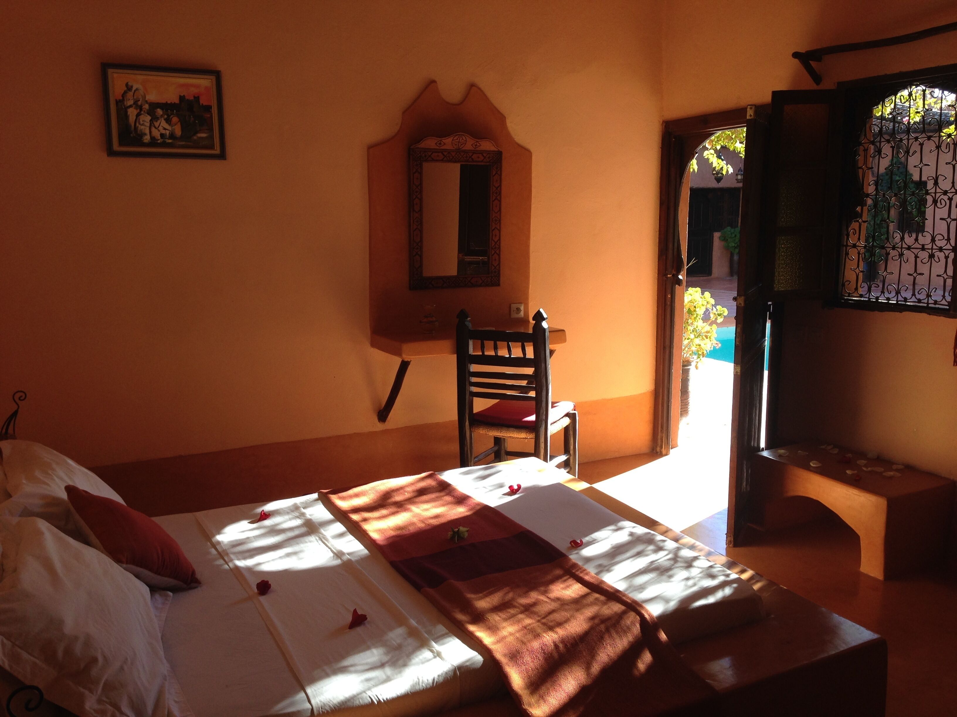 A bedroom with a bed, a chair, a mirror, and a door leading outside.