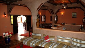 A cozy room with a sofa, a wooden table, and a vase of flowers. - Riad of charm any comfort with swimming pool without opposite and big sported garden. (Marrakech)