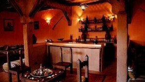 A cozy bar area with wooden furniture, a bar counter, and a decorative centerpiece. - Riad of charm any comfort with swimming pool without opposite and big sported garden. (Marrakech)