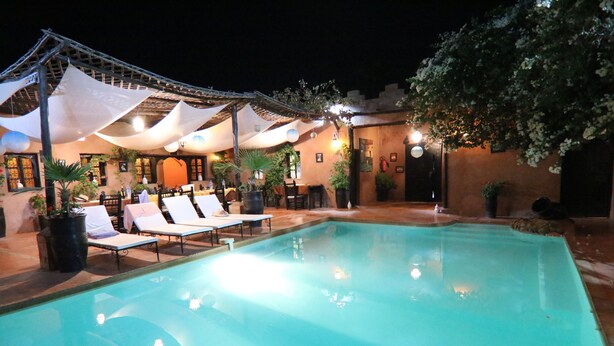 A pool area with lounge chairs and umbrellas, surrounded by potted plants and a building with a tiled roof. - Riad of charm any comfort with swimming pool without opposite and big sported garden. (Marrakech)
