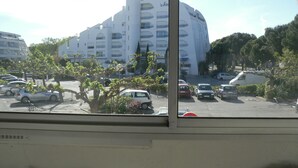 A view of a modern building with multiple balconies and a parking lot in front.