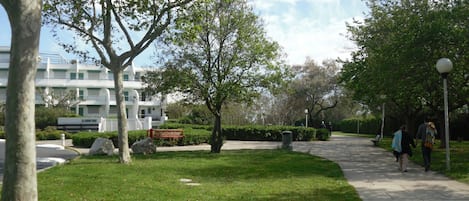 Un parque con un sendero pavimentado, bancos y árboles.