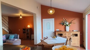 A dining area with a table set for two, a bowl of fruit, and a vase with flowers on the sideboard. - sea view everywhere in the house (Estreito da Calheta)