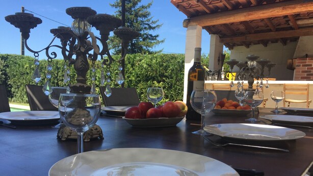 A dining table set outdoors with plates, cutlery, wine glasses, and a decorative candelabra. - Charming house with heated swimming pool, in a quiet, unoverlooked location. (Saint-Rémy-De-Provence)