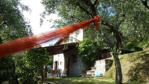 Een rustieke buitenruimte met een hangmat, stenen traptreden en een gebouw met een schuin dak.