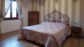 Een slaapkamer met een bed, een houten garderobe en een raam met gordijnen.