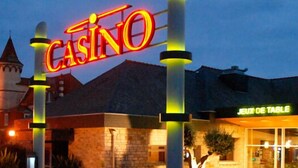 A casino with a prominent neon sign, a tower, and a restaurant named "JEUX DE TABLE". - Crucano palm groves, the house itself has a heated swimming pool for 10 people (Plouharnel)