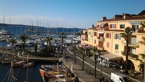 Una marina con barcos amarrados, una calle con edificios y un cielo despejado.