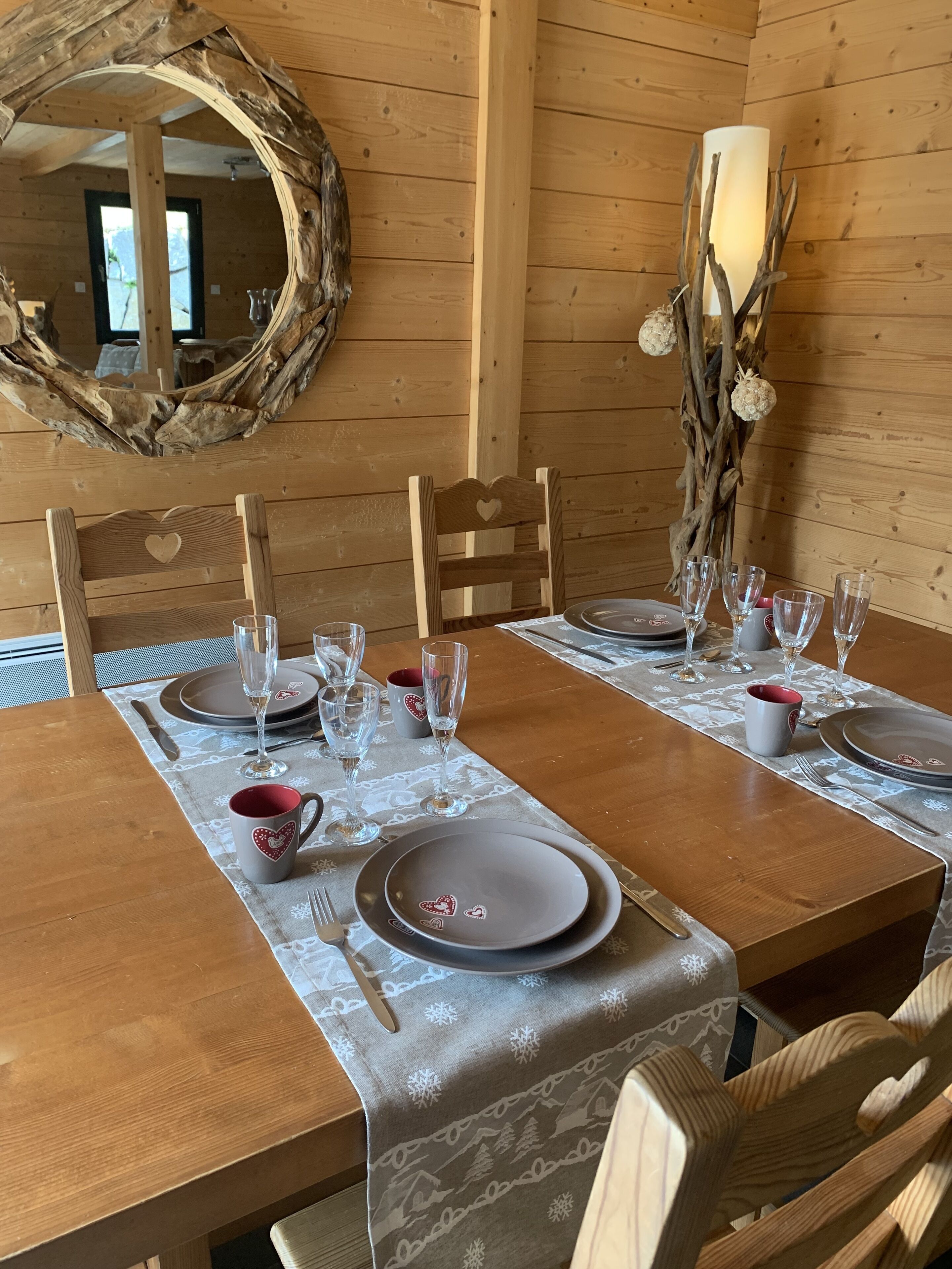 Ein Holzespeisesaal mit Tellern, Gläsern und Besteck, umgeben von Stühlen mit herzförmigen Rückenlehnen.