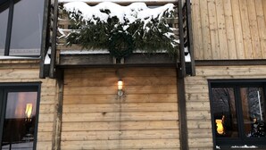 Een houten hut met een balkon, grote ramen en een sneeuwbedekte dak.