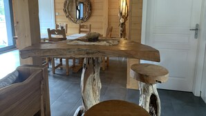 Een rustieke houten eethoek met een grote tafel, stoelen en een spiegel aan de muur.