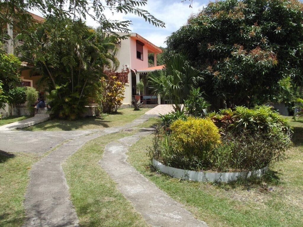 Un chemin menant à un bâtiment entouré d’une végétation luxuriante et agrémenté d’un petit jardin.