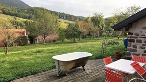 A rustic outdoor deck with a vintage bathtub, wooden chairs, and a stone building. - Quiet house, with open view and all the comfort in the heart of Alsace (Saint-Pierre-Bois)