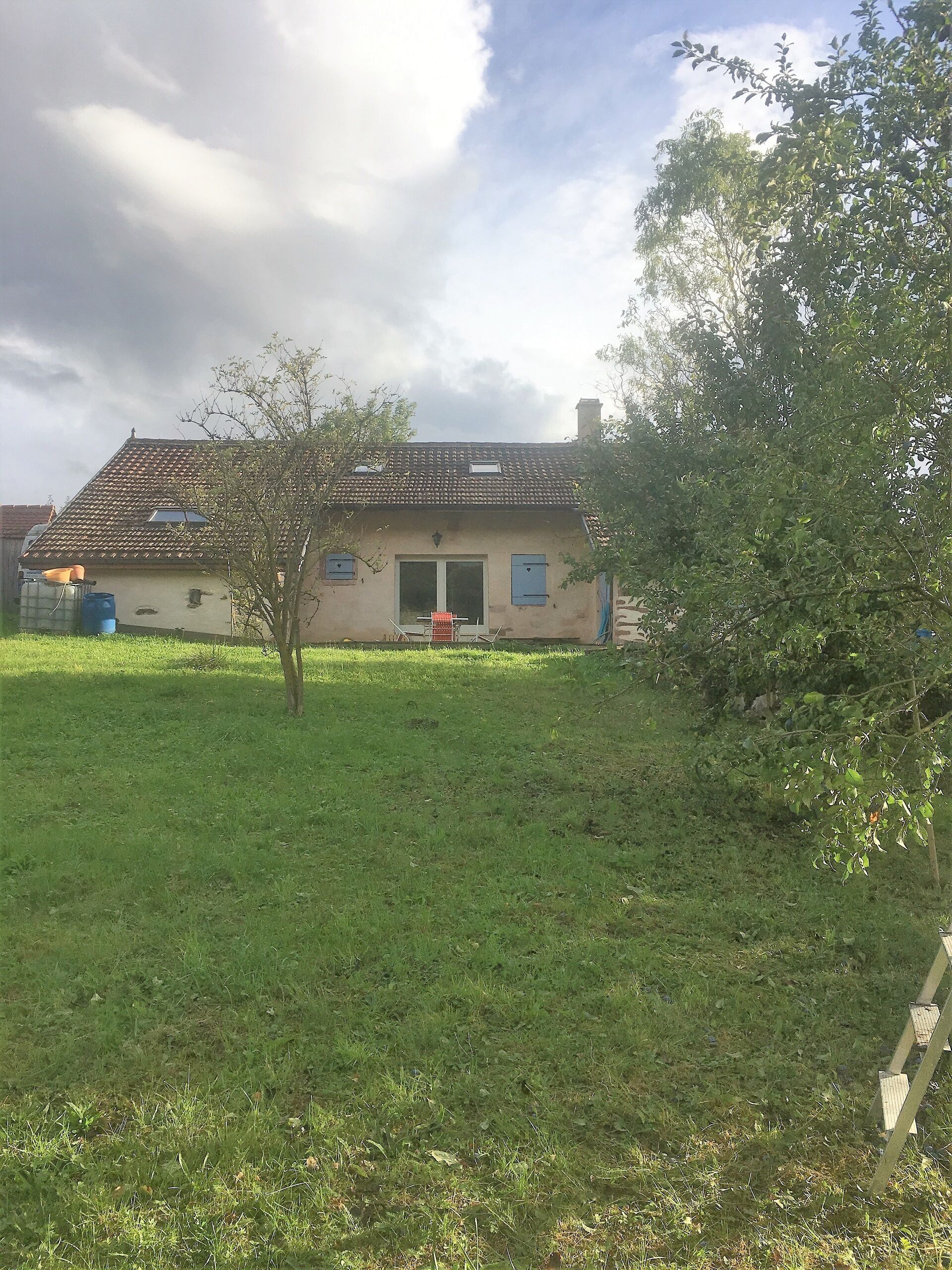 Une maison avec un toit en tuiles, une porte d’entrée et un petit porche.