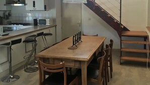 A modern kitchen with a wooden table and chairs, a staircase, and a view of the outside. - Quiet house, with open view and all the comfort in the heart of Alsace (Saint-Pierre-Bois)