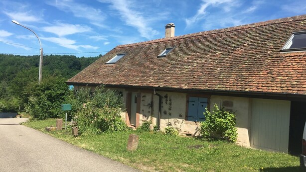 A rustic building with a tiled roof, a chimney, and a small window. - Quiet house, with open view and all the comfort in the heart of Alsace (Saint-Pierre-Bois)