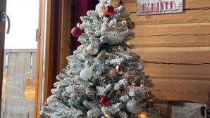 Un árbol de Navidad decorado con adornos y luces, un cartel en la pared y un interior de madera.
