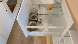 Un cajón de cocina con frascos de vidrio y una botella.