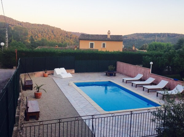 A rectangular swimming pool with a tiled deck, surrounded by a low brick wall. There are lounge chairs and a small table with a potted plant. A building with a tiled roof is visible in the background. - Nice house between Verdon and the Mediterranean (Salernes)