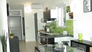 Una cocina moderna con una mesa y sillas de vidrio, horno integrado y salpicadero verde.