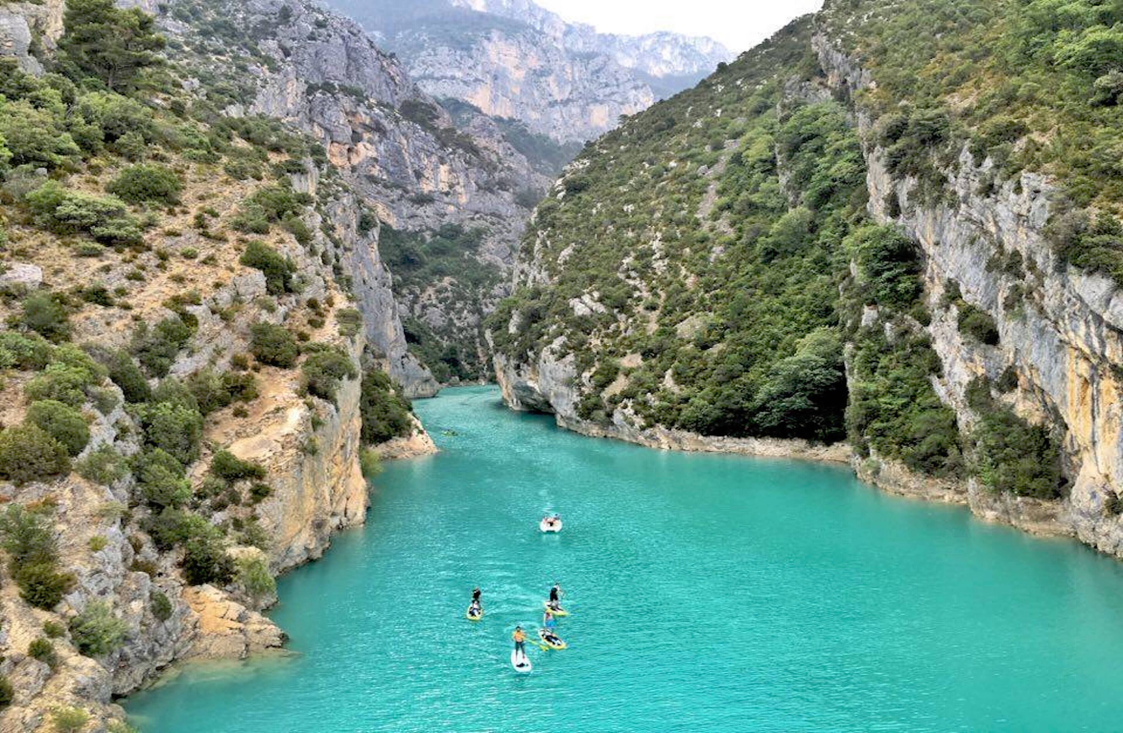 A river canyon with a group of people on paddleboards.