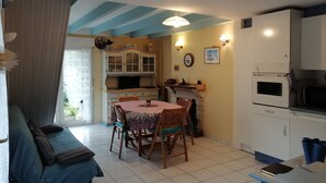 Ein gemütliches Wohnzimmer mit Sofa und Esstisch, eine Küche mit Schränken und Herd sowie ein Kamin.