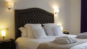 A neatly made bed with white linens and pillows, a dark tufted headboard, and two bedside lamps. - like  a presidential suite with a magnificient view (Paris)