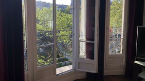 A corner room with a large window offering a view of a cityscape and greenery. - like  a presidential suite with a magnificient view (Paris)