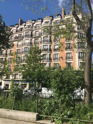 Un edificio residencial de varios pisos con balcones, fachada de ladrillo y cielo azul despejado.