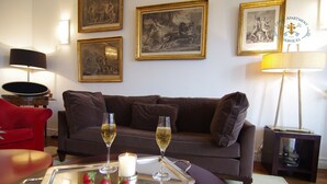 A living room with a brown sofa, two wine glasses on a tray, a candle, and framed artwork on the wall. - like  a presidential suite with a magnificient view (Paris)