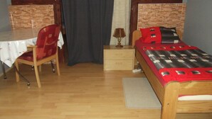 Een slaapkamer met een houten bed, een bureau met stoel, nachtkastje en lamp.