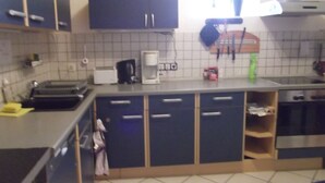Een keuken met een broodrooster, koffiezetapparaat en diverse keukengerei op het aanrecht.