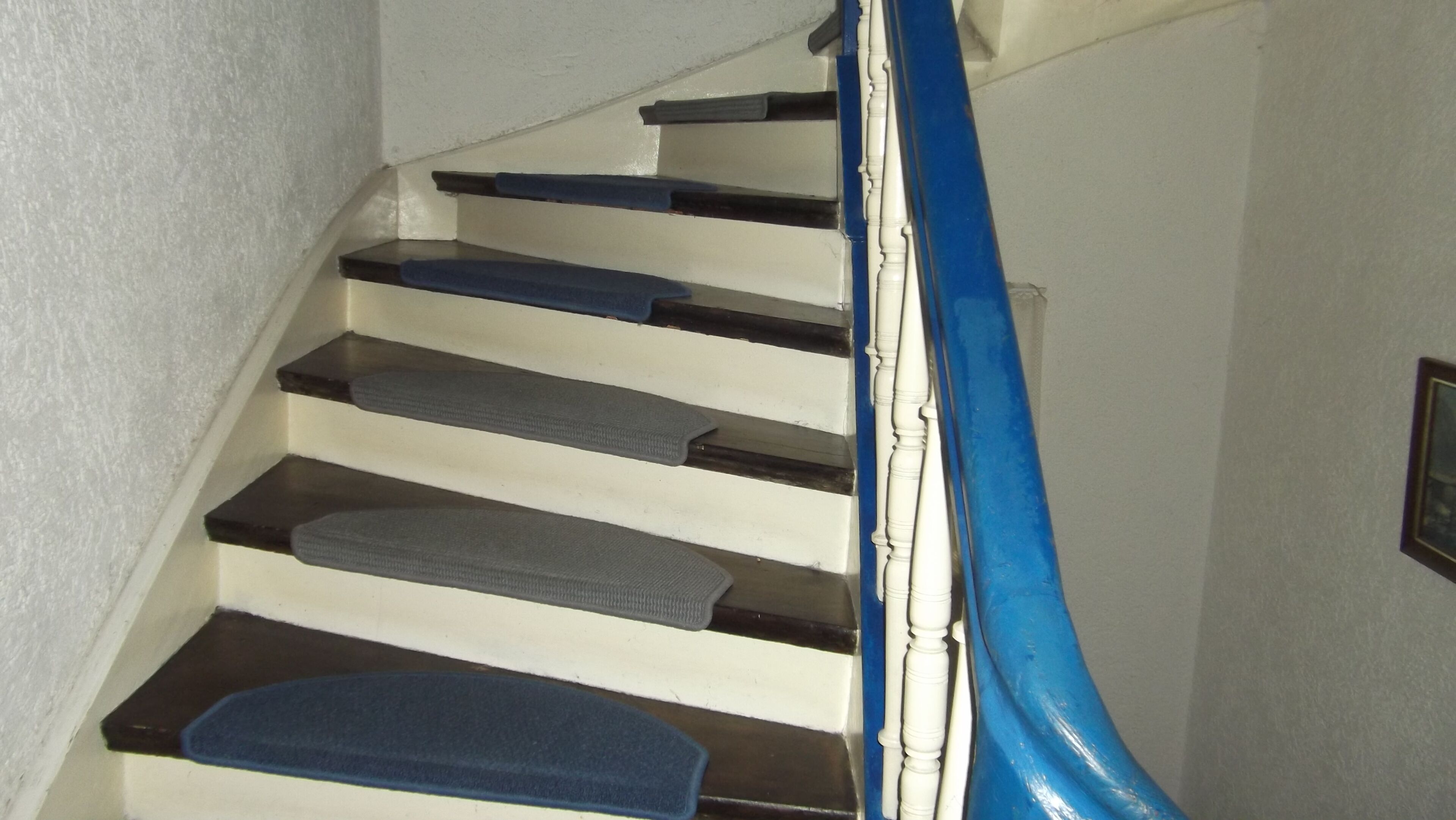 A staircase with blue handrails and white walls.