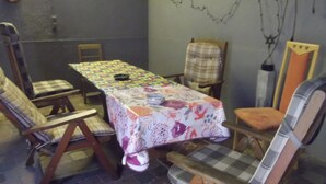 Een eetgedeelte met een tafel, bedekt met een tafelkleed met bloemenprint, omringd door houten stoelen.