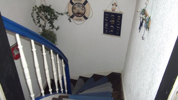 A staircase with white balusters and blue handrails, a life preserver with 'AN BORD' text, and a wall-mounted decorative item.