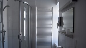Une salle de bain moderne avec une douche à parois de verre, un lavabo blanc et un porte-serviettes.