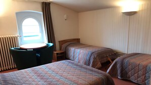Une chambre avec deux lits, une petite table, une chaise et une fenêtre avec des rideaux.