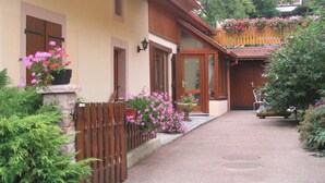 Een klassiek chalet met een houten gevel, een stenen entree en een balkon vol bloemen.