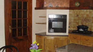 Een keuken met een houten deur, een oven, een fornuis en een vaas met bloemen op het aanrecht.