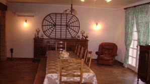 A dining room with a long wooden table, chairs, a chandelier, a decorative wall piece, and a fireplace. - Charming 70m2 villa with private pool (Castelnau D'auzan Labarrère)