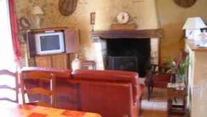 Ein Wohnzimmer mit Kamin, Fernseher und Essbereich mit Tisch und Stühlen.