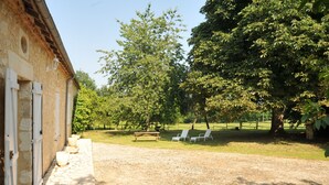Ein Steinhaus mit Kiesweg und Gartenmöbeln.