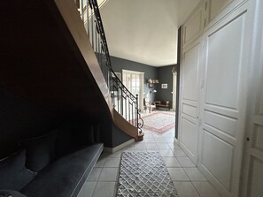 En trappe fører op til et rum med en hvid dør, et gulvtæppe med et mønster og et skrivebord med en stol.