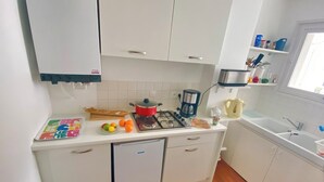 Una cocina compacta con refrigerador, estufa, cafetera y lavamanos.